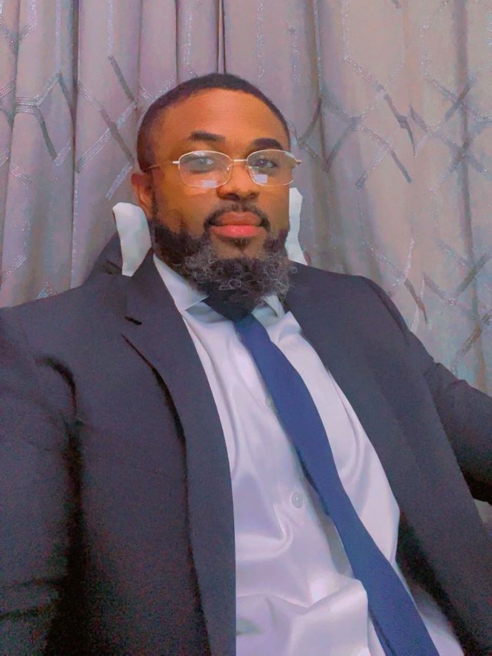 A woman with long blonde hair is wearing a black dress and a necklace.